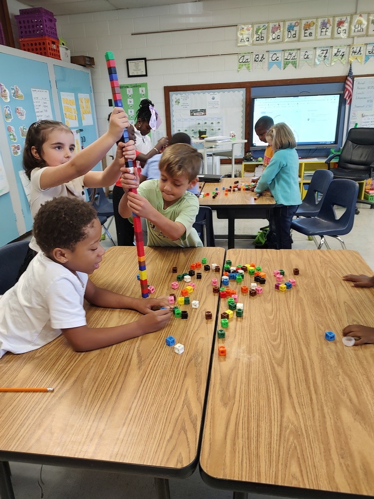 Tables are filled with colorful cubes as students demonstrate teamwork, communication, and problem-solving skills during this fun hands-on activity.