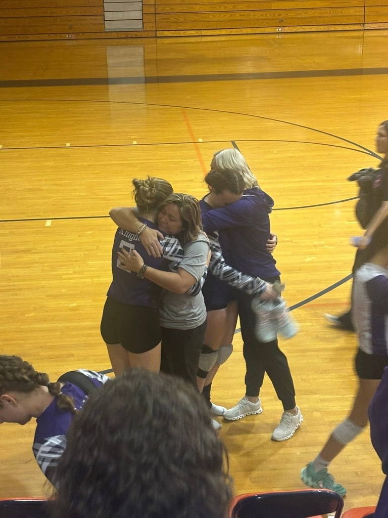 After the game, players and coaches embrace in a heartfelt moment on the gym floor. The emotional scene shows the team’s connection and support following their playoff match.