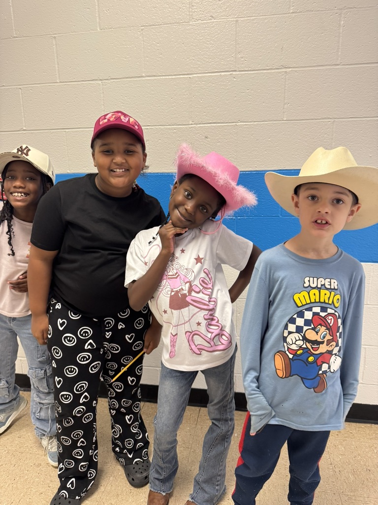 Four smiling students line up in a hallway wearing hats, including a pink cowboy hat and a white cowboy hat, showing off their Red Ribbon Week spirit.
