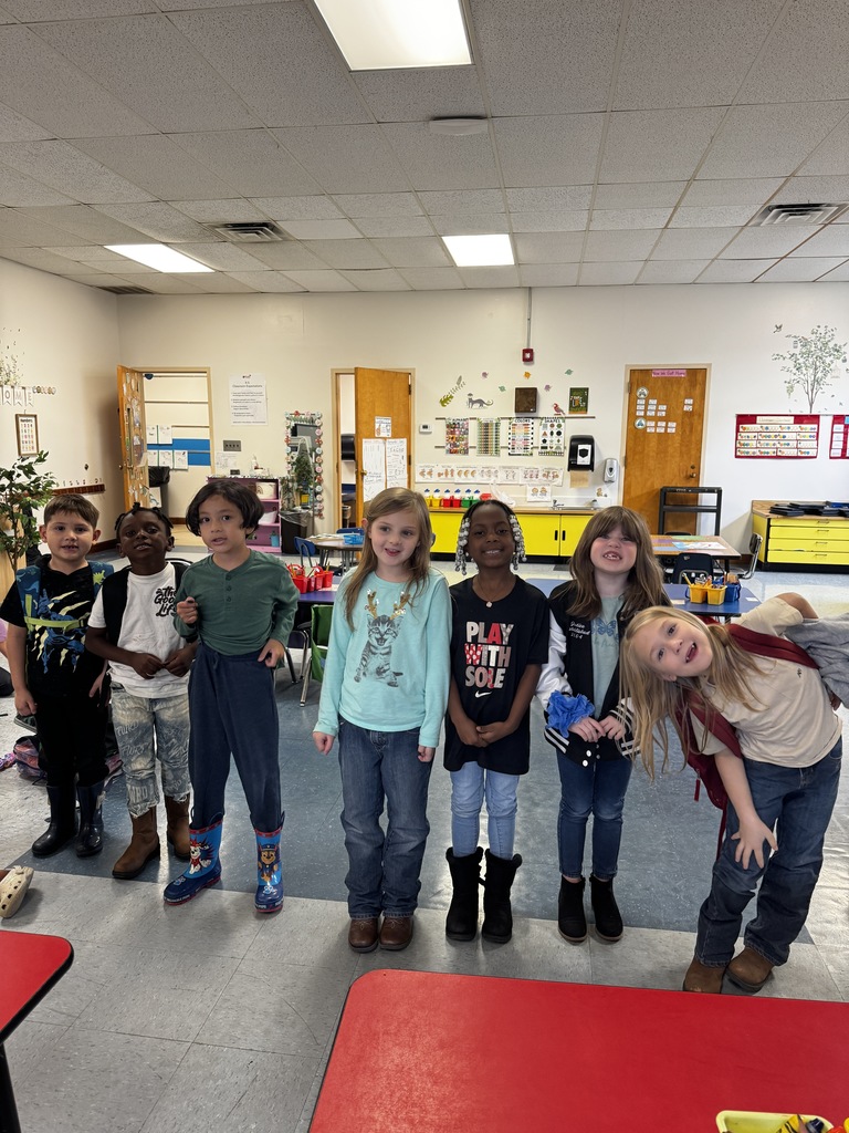 Seven elementary students stand in a row smiling and wearing boots, jeans, and cozy fall shirts for “Give Drugs the Boot” day.
