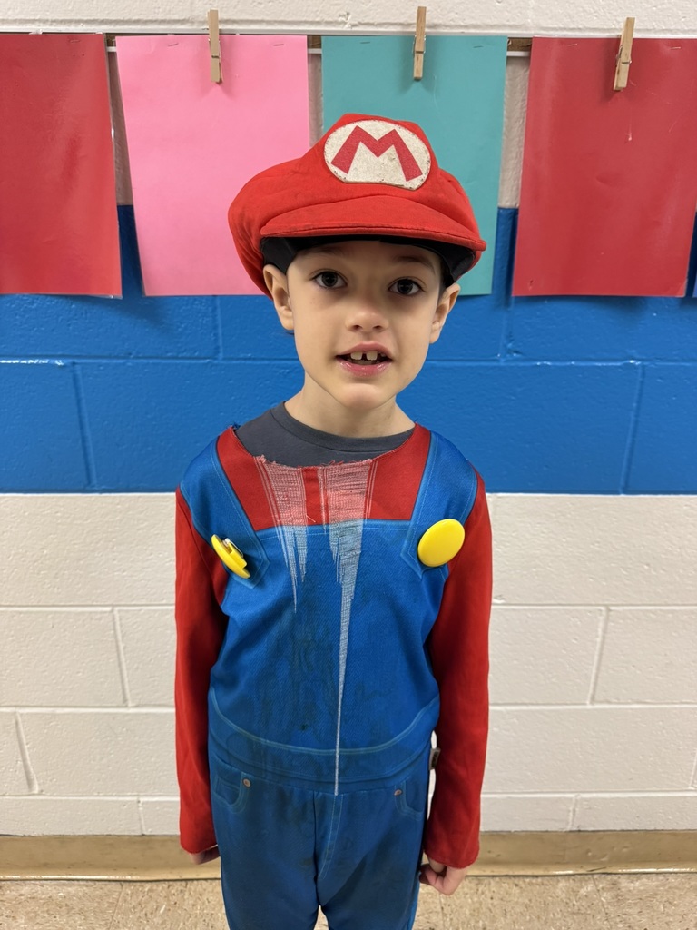 A student dressed as a video game character in blue overalls, a red shirt, and a red cap with the letter “M.”