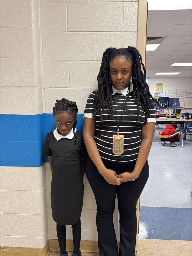A teacher and student dressed alike in black-and-white striped outfits, recreating a matching character look with serious expressions.