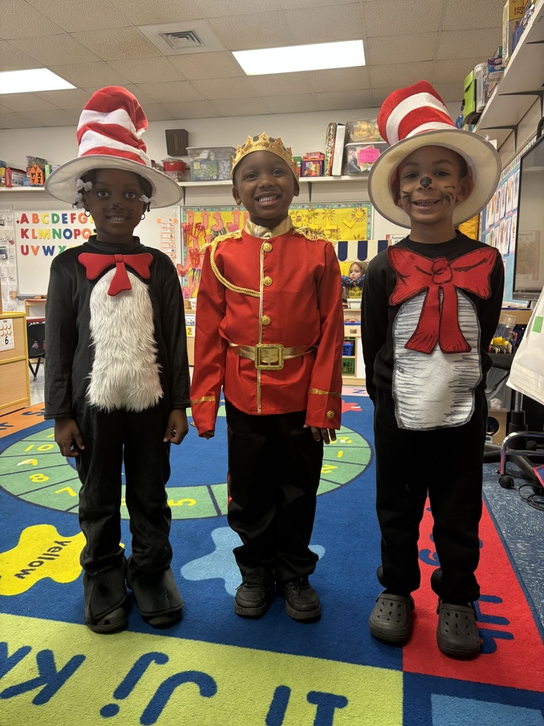 Three children smiling—two dressed as Cat in the Hat and one as a royal character wearing a red jacket with gold trim and a crown.