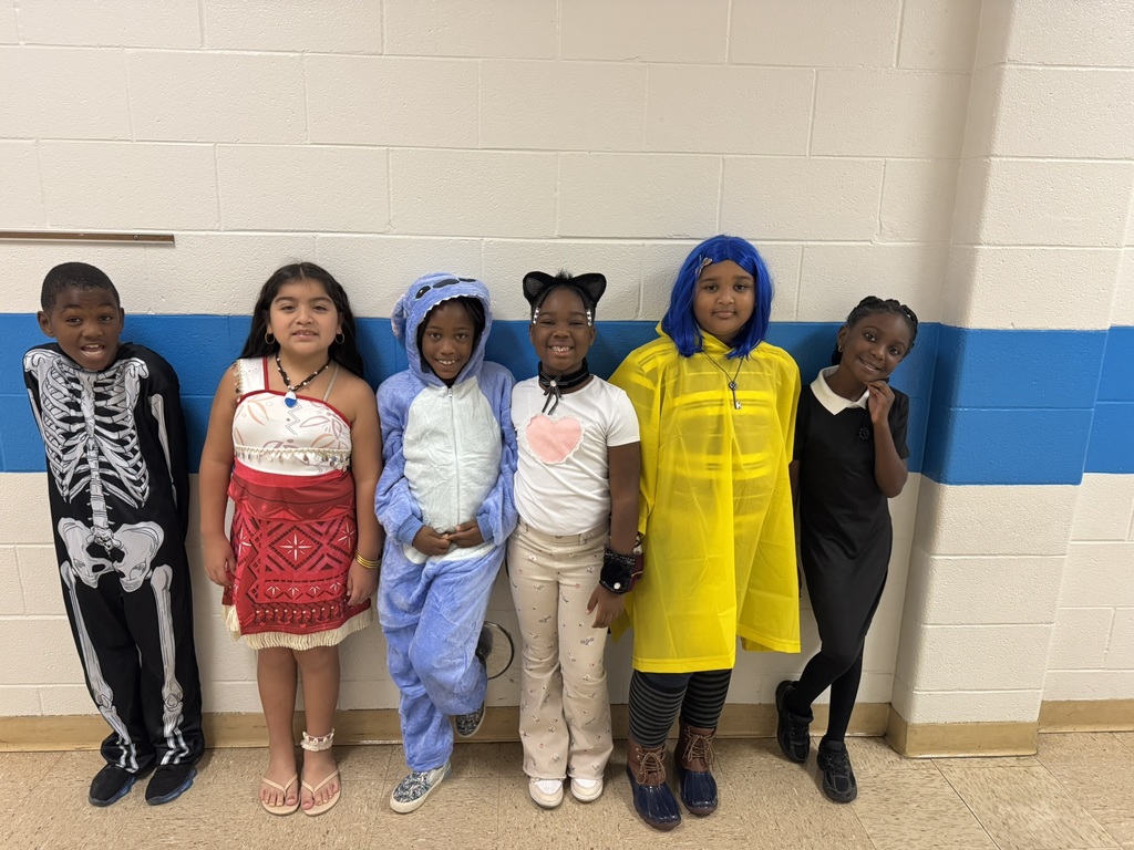 Six students lined up in colorful costumes including a skeleton, island explorer, blue creature, cat, character in a yellow raincoat, and one in a black dress.