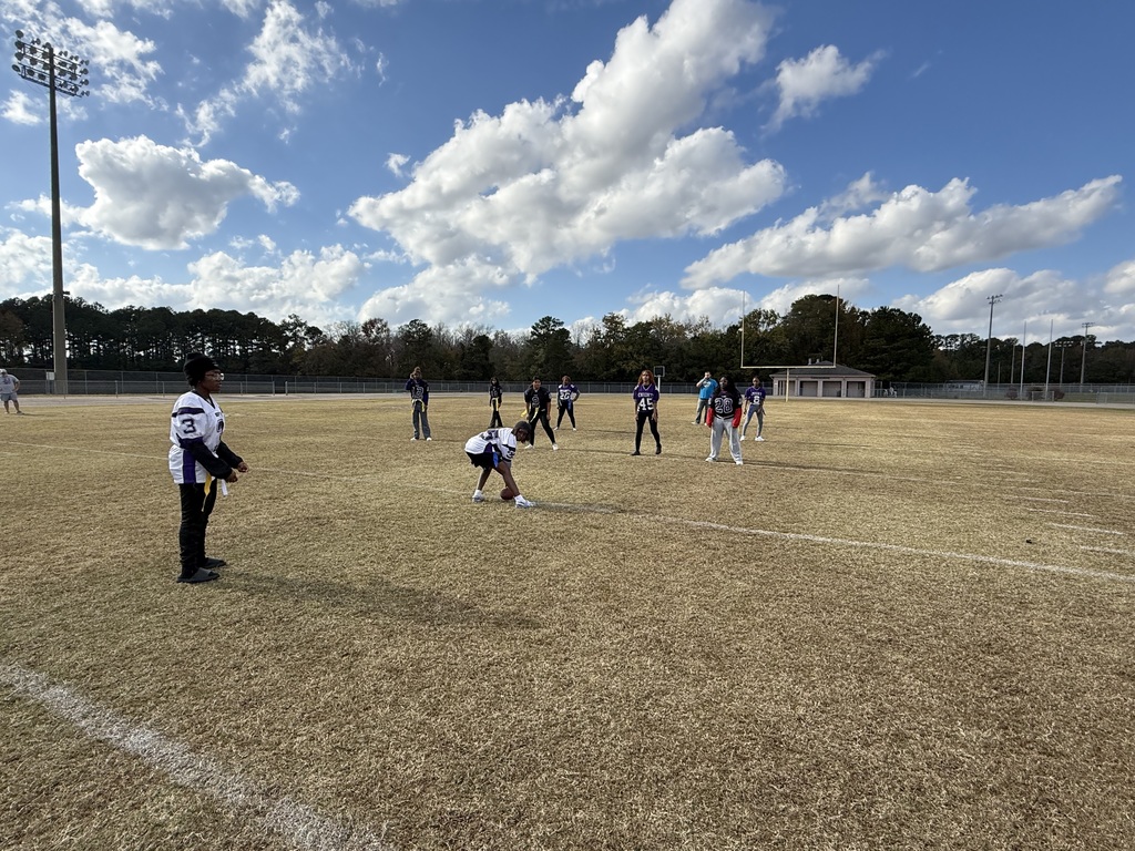 Two flag football teams face each other on the field with one player hiking the ball
