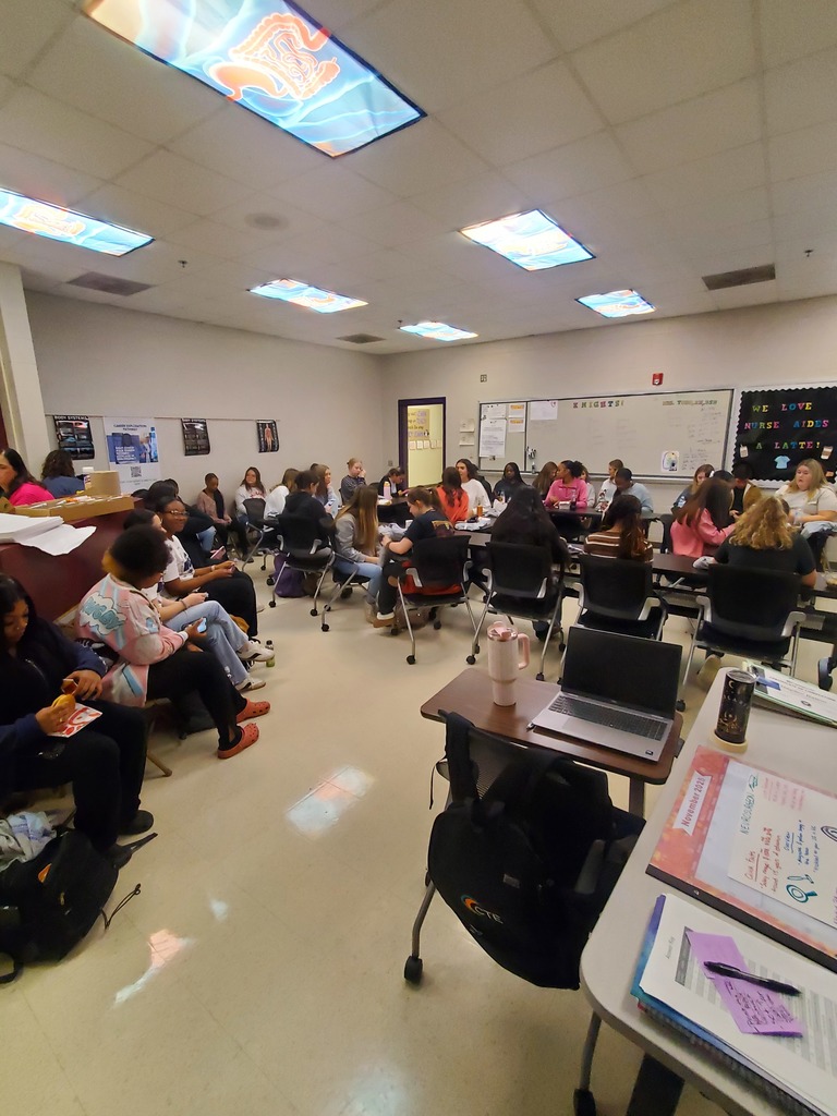 A classroom filled with many students seated at desks, engaged in a group meeting or lecture
