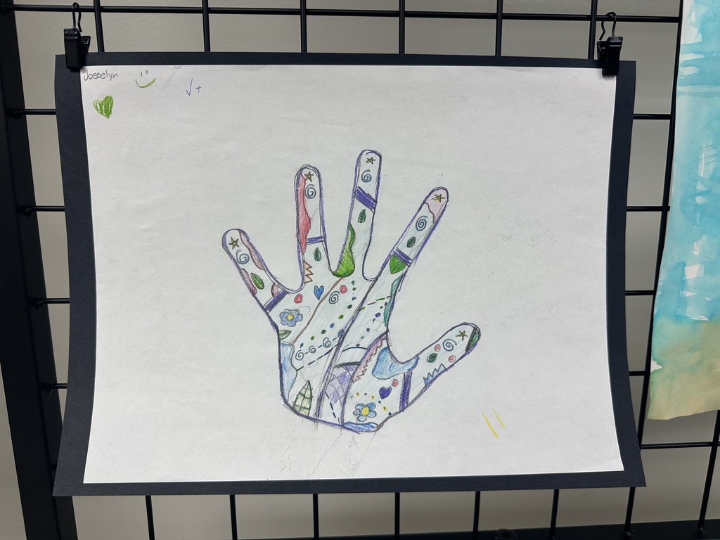 A traced hand filled with colorful doodles including stars, swirls, flowers, and geometric patterns on white paper.