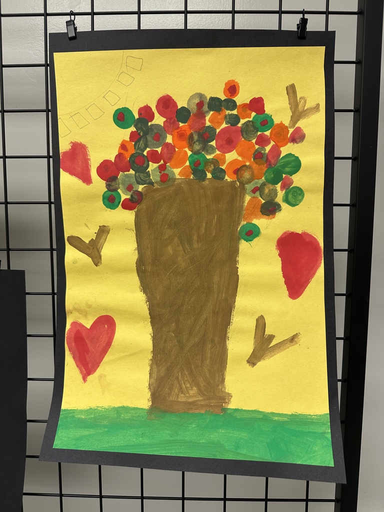 A tall brown vase holding bright, round painted flowers in red, orange, and green on a yellow background with red hearts.