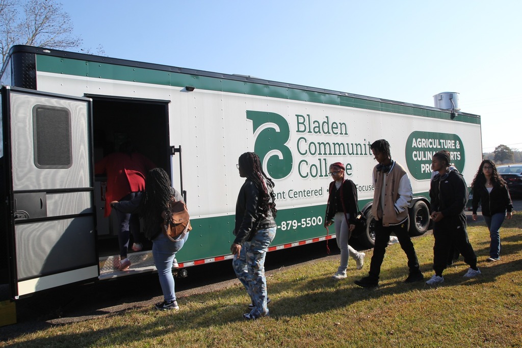 Students walk toward and enter a Bladen Community College mobile culinary and agriculture training trailer.