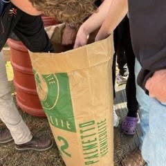 Hands reach into a large paper bag labeled "Palmetto Vermiculite," with a red barrel and feet visible nearby.