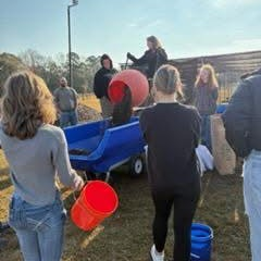 A group of people are working with gardening tools and supplies in an outdoor setting.