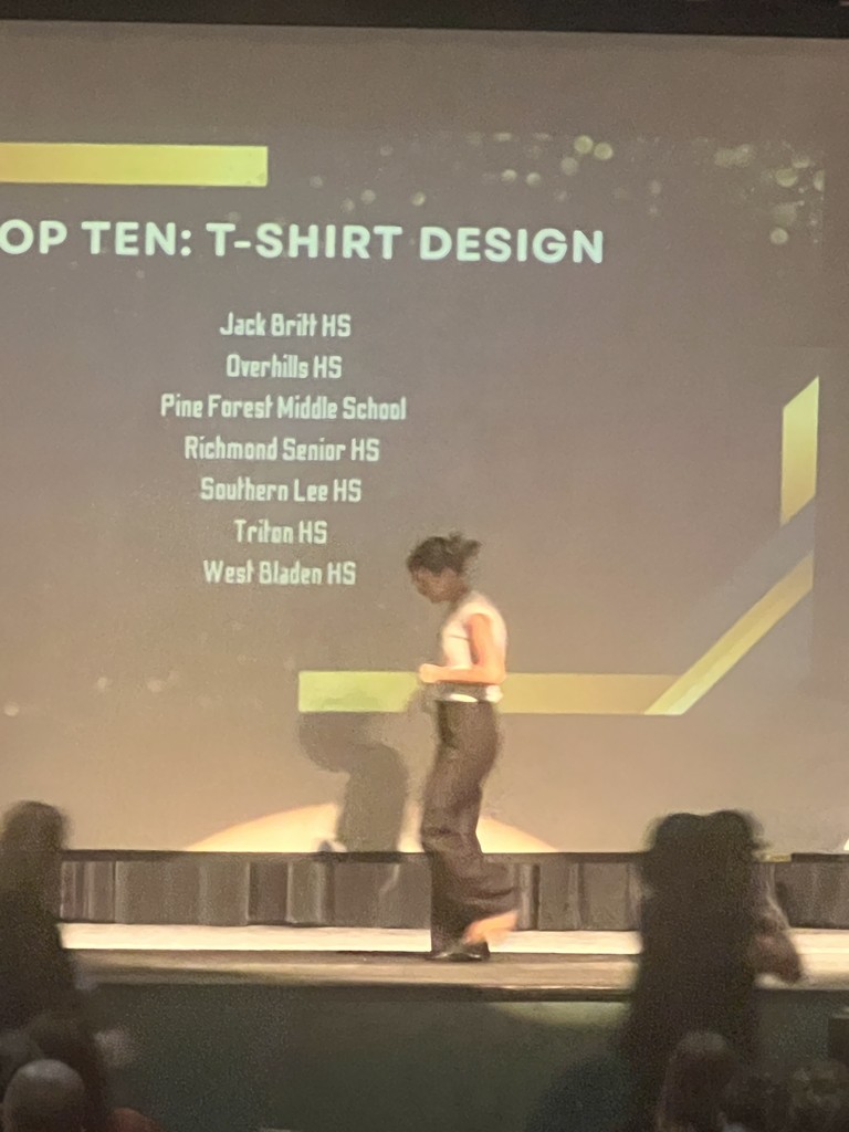 A list of schools on a screen showing the "TOP TEN: T-SHIRT DESIGN" finalists, including West Bladen HS.