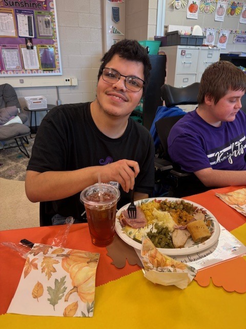a smiling student ready to eat a thanksgiving plate