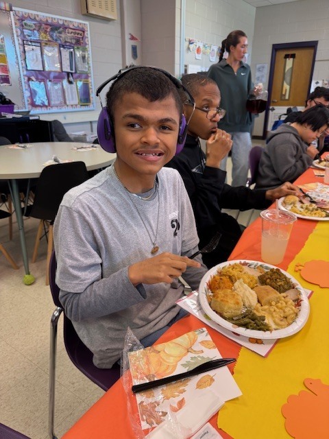a smiling student points to his thanksgiving plate
