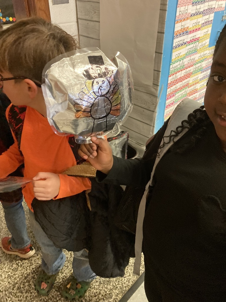 A close-up of a student holding a foil parade balloon decorated as a turkey with colorful feathers and a pilgrim hat.
