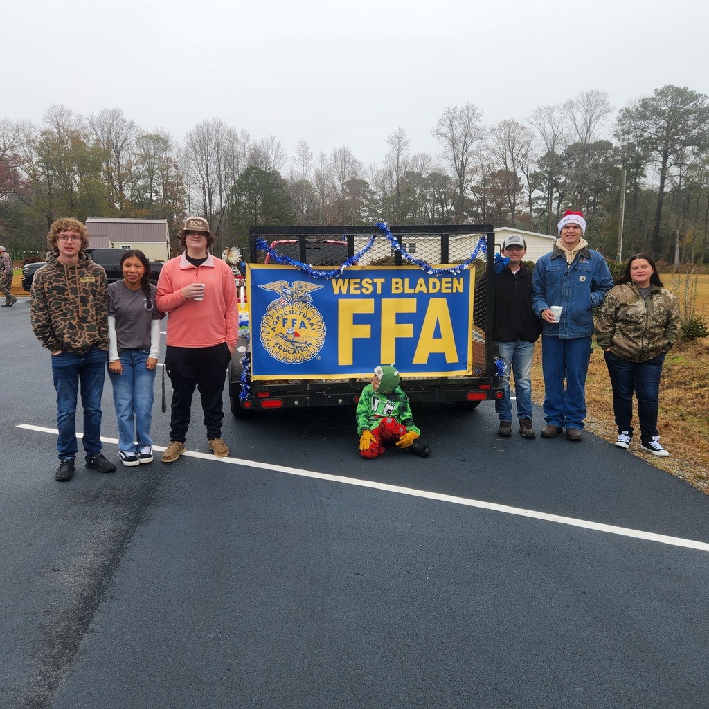 Seven West Bladen FFA students and a child pose with their decorated trailer float.