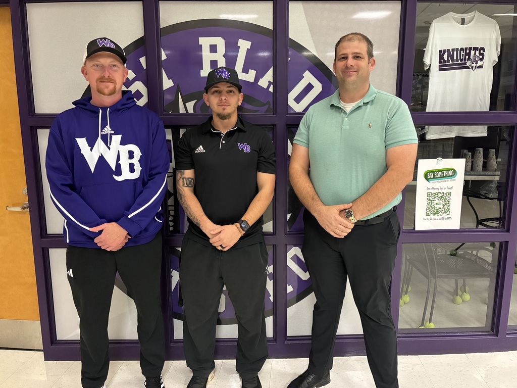 Three men pose in front of a purple West Bladen Knights logo. Two wear team caps and shirts, while the third wears a green polo.