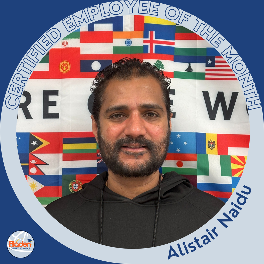 Circular ‘Certified Employee of the Month’ graphic featuring a man smiling in front of a backdrop made of international flags. He is wearing a black hoodie. Text on the graphic reads ‘Alistair Naidu.