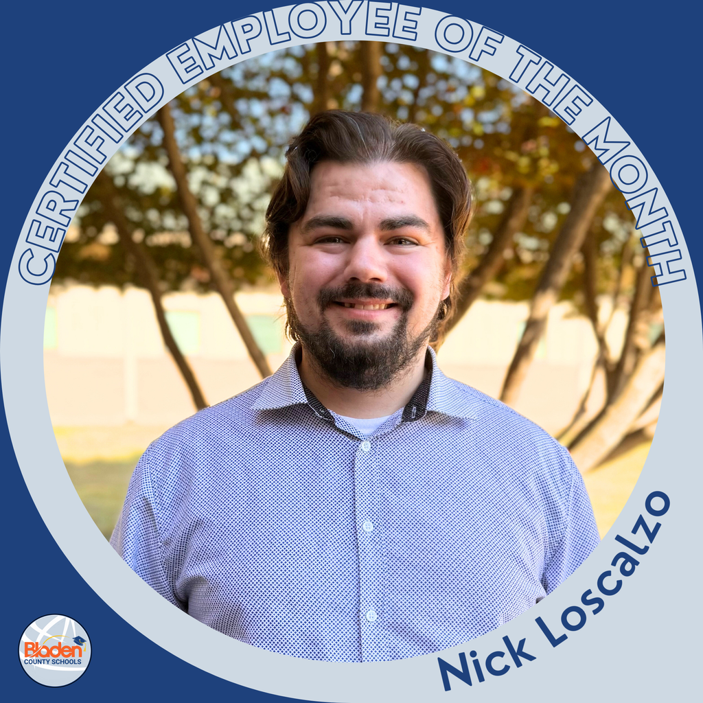 “A man with medium-length dark hair and a beard smiles while standing outside in front of trees. He is wearing a light patterned button-down shirt. The circular frame reads ‘Certified Employee of the Month – Nick Loscalzo,’ with the Bladen County Schools logo in the corner