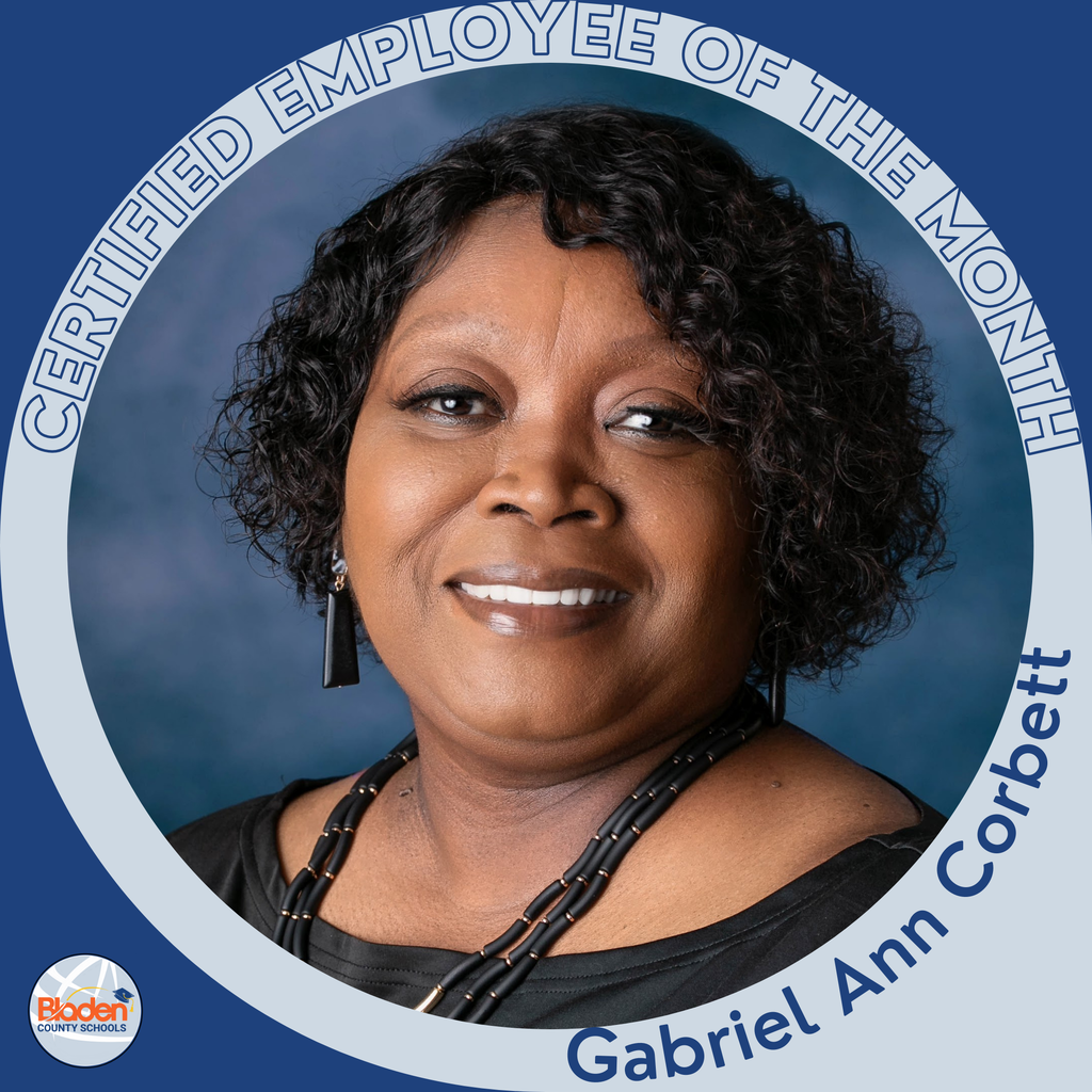 Circular ‘Certified Employee of the Month’ graphic featuring a woman smiling in front of a blue background. She has short curly hair and is wearing a black top with a beaded necklace and long earrings. Text on the graphic reads ‘Gabriel Ann Corbett.