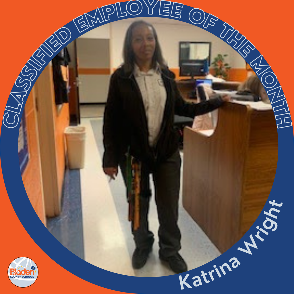 Circular ‘Classified Employee of the Month’ graphic featuring a woman standing in a school hallway near a desk, wearing a jacket and work keys. Text on the graphic reads ‘Katrina Wright.