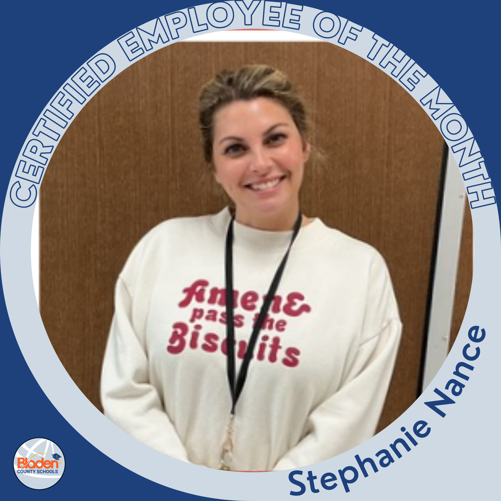 A woman with her hair pulled back smiles while wearing a cream-colored sweatshirt that reads “Amen, pass the Biscuits.” She stands against a brown wall inside a “Certified Employee of the Month” circular frame in blue and gray, with her name “Stephanie Nance” displayed at the bottom.