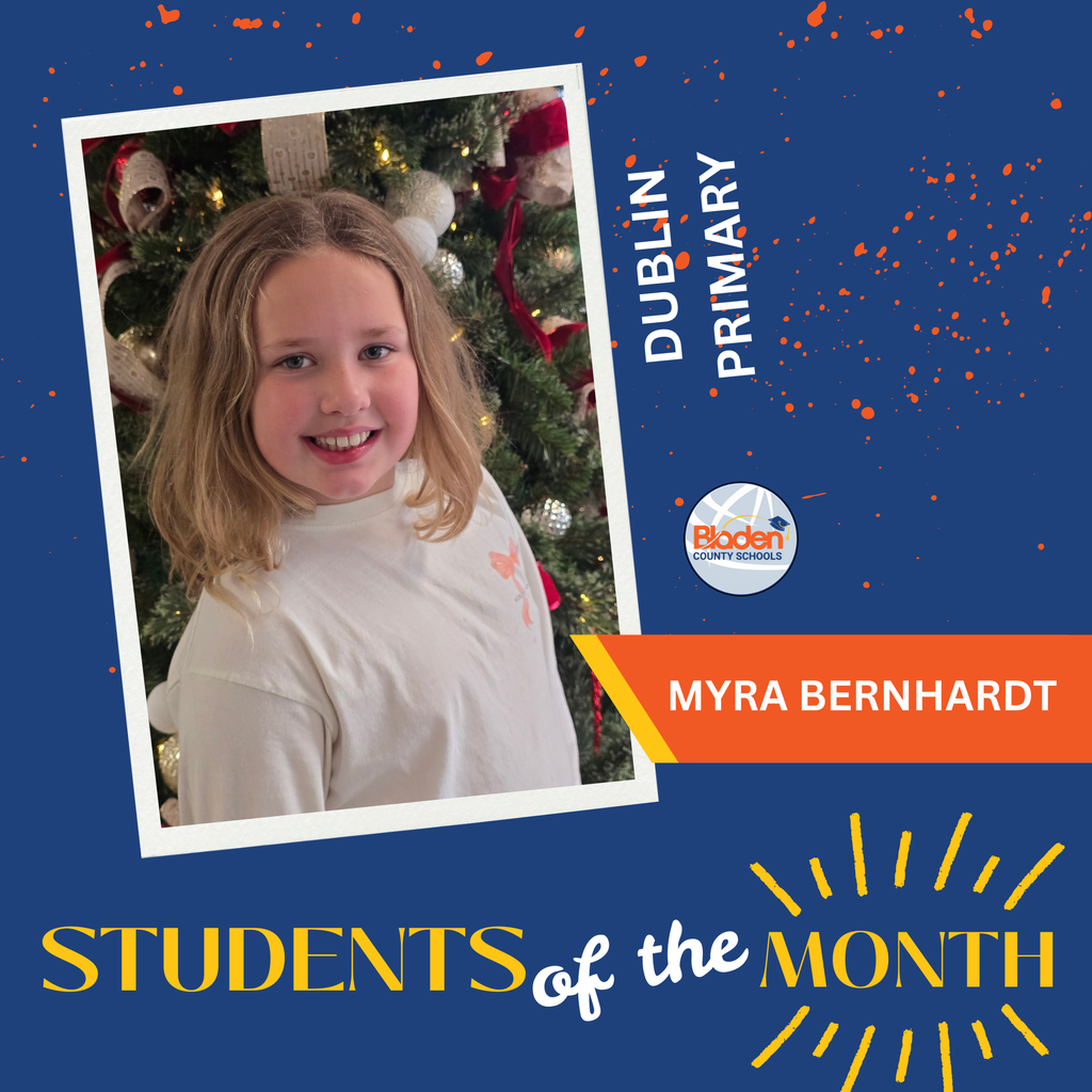 A student with shoulder-length blonde hair wearing a light-colored shirt smiles while standing in front of a decorated Christmas tree. The graphic reads “Dublin Primary” and “Myra Bernhardt” with a “Students of the Month” banner.