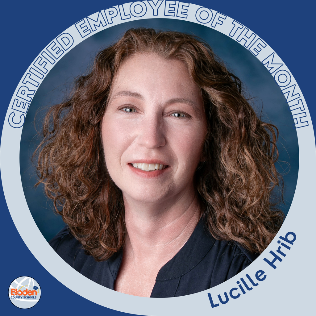 A woman with curly brown hair poses against a dark blue portrait background, smiling softly. The circular frame reads ‘Certified Employee of the Month – Lucille Hrib,’ with the Bladen County Schools logo in the corner.