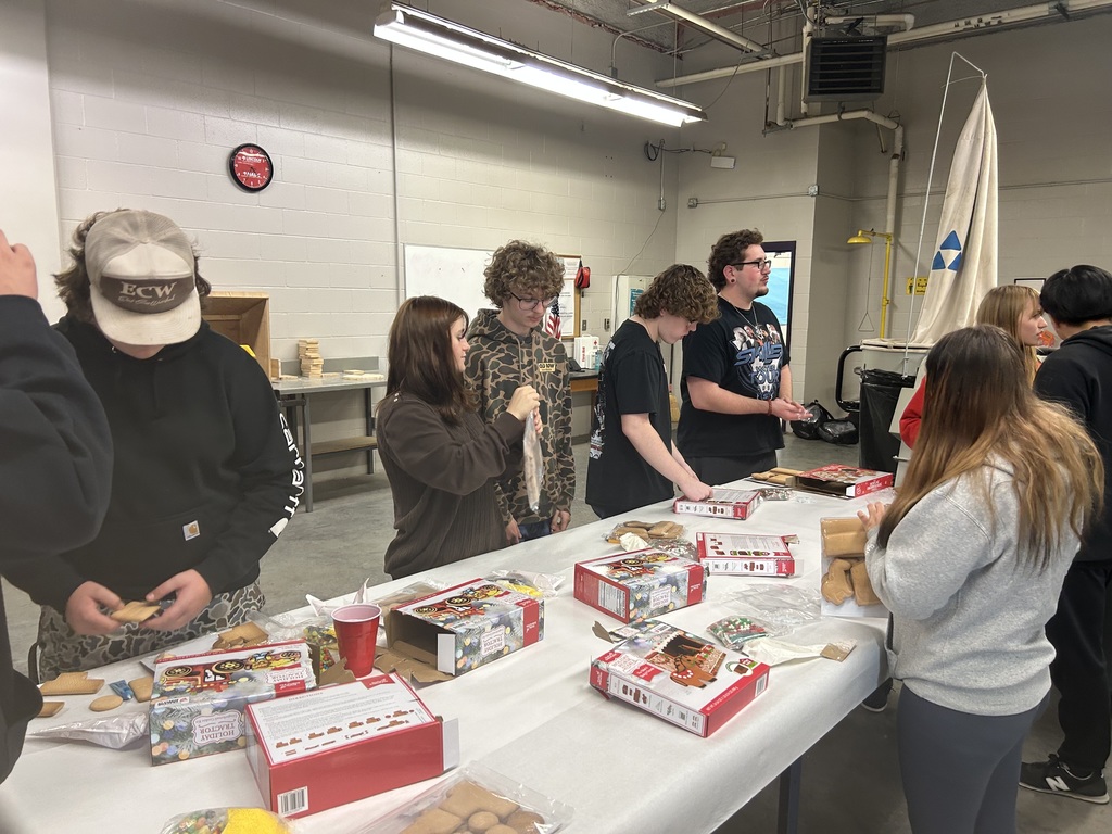 students working at a long table building gingerbread houses