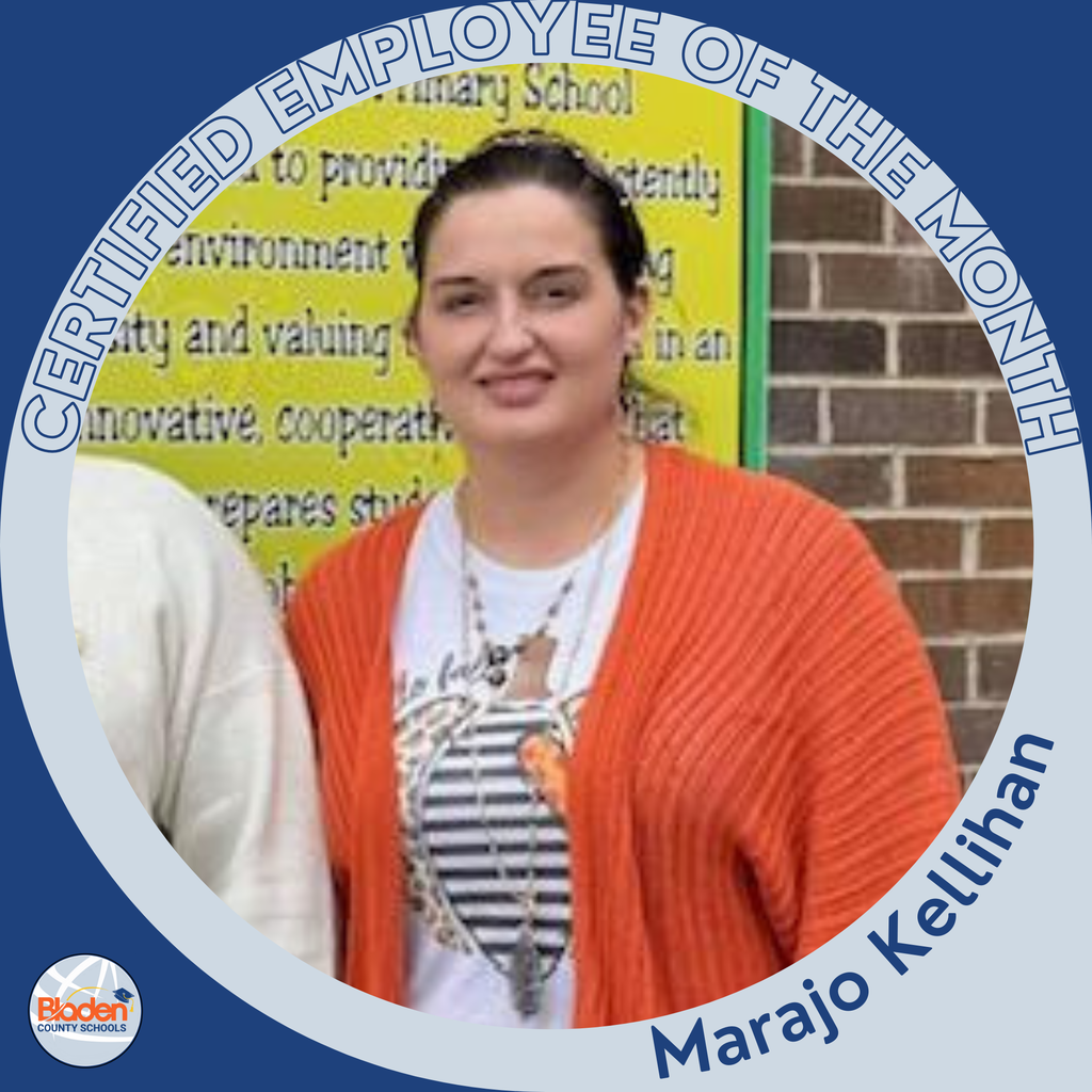 Circular ‘Certified Employee of the Month’ graphic featuring a woman standing in front of a bright yellow school poster and a brick wall. She is wearing an orange cardigan over a patterned T-shirt and smiling at the camera. Text on the graphic reads ‘Marajo Kellihan.