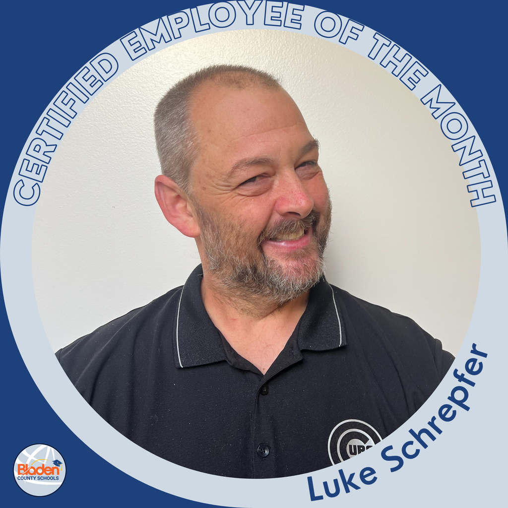 A man with short hair and a beard smiles and looks to the side while wearing a black collared shirt. The circular frame reads ‘Certified Employee of the Month – Luke Schrepfer,’ with the Bladen County Schools logo in the corner.