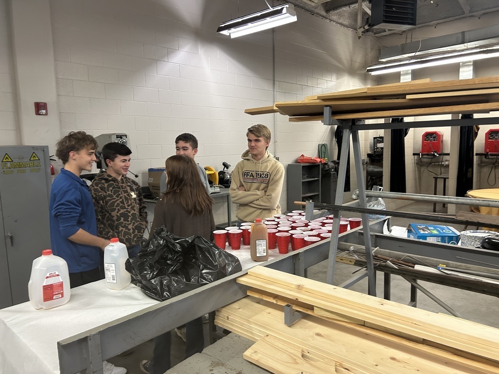 students socializing around a table of apple cider
