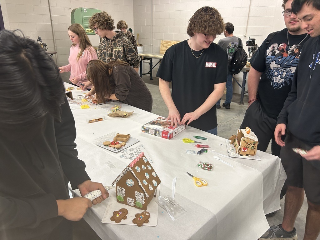 students socialize around a gingerbread house