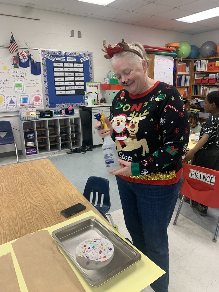 A teacher assists a student as they spray water onto a coffee-filter snowflake, watching the colors blend and flow across the paper.