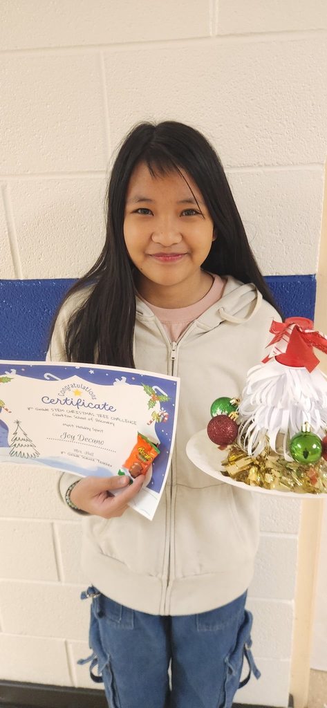 A student holds a certificate and a recycled Christmas tree decorated with paper and ornaments.