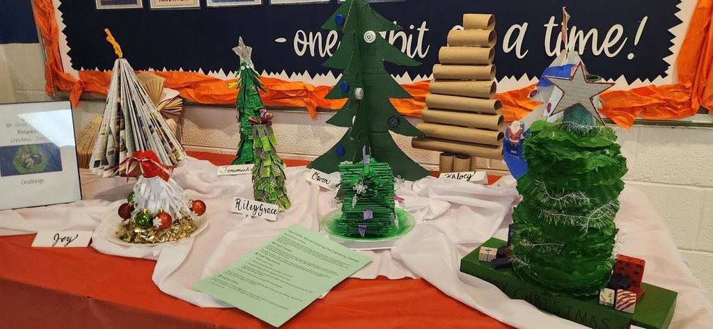 A display table featuring student-created Christmas trees made from recycled materials, arranged for the Clarkton School of Discovery STEM Christmas Tree Challenge.