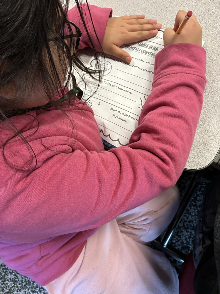 young student dressed in pink completing a worksheet