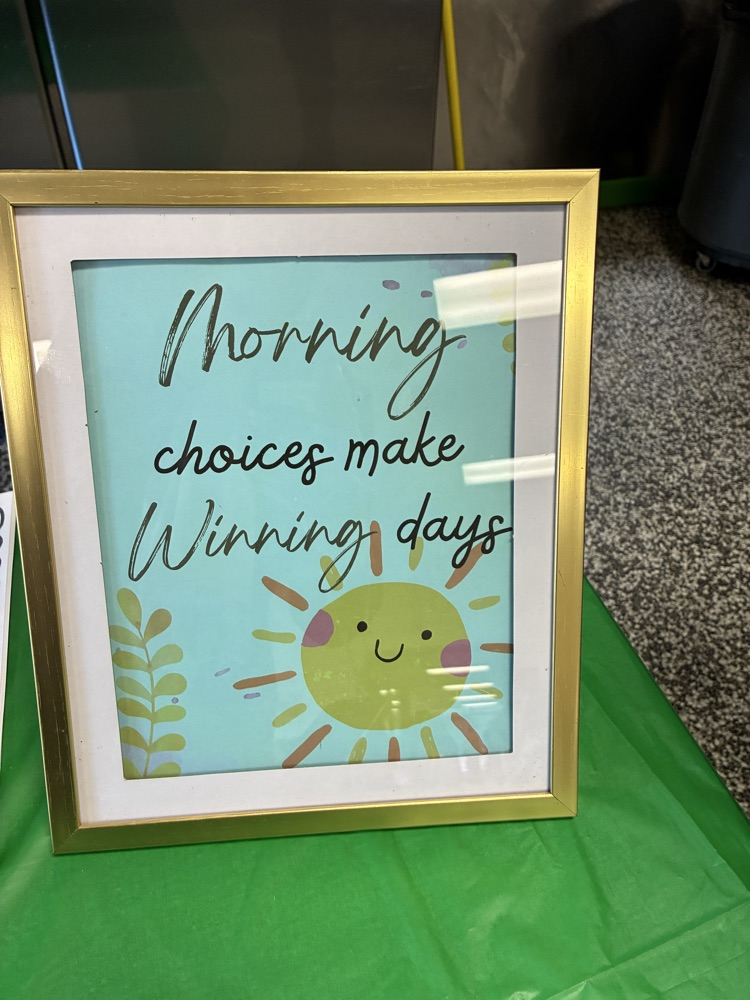 flyer that says “morning choices make winning days” in gold frame sitting on table with green tablecloth