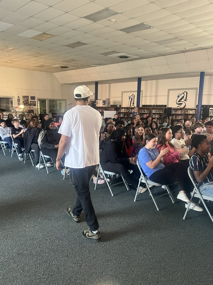 Students sitting in chairs watching people perform poetry
