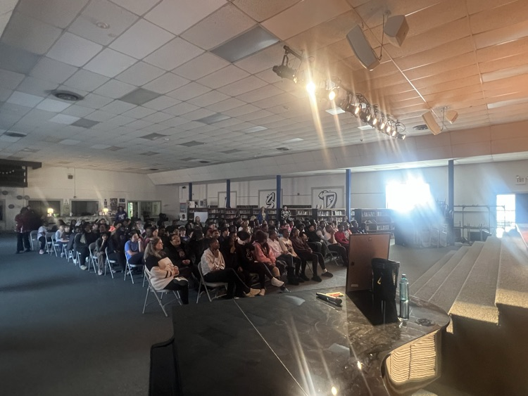 Students sitting in chairs watching people perform poetry