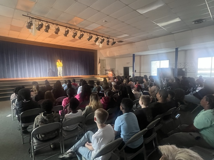 Students sitting in chairs watching people perform poetry