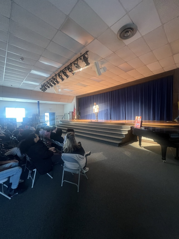 Students sitting in chairs watching people perform poetry