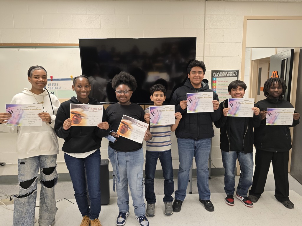 Eight Elizabethtown Middle School students stand side by side in a classroom holding Honor Roll and Perfect Attendance certificates.