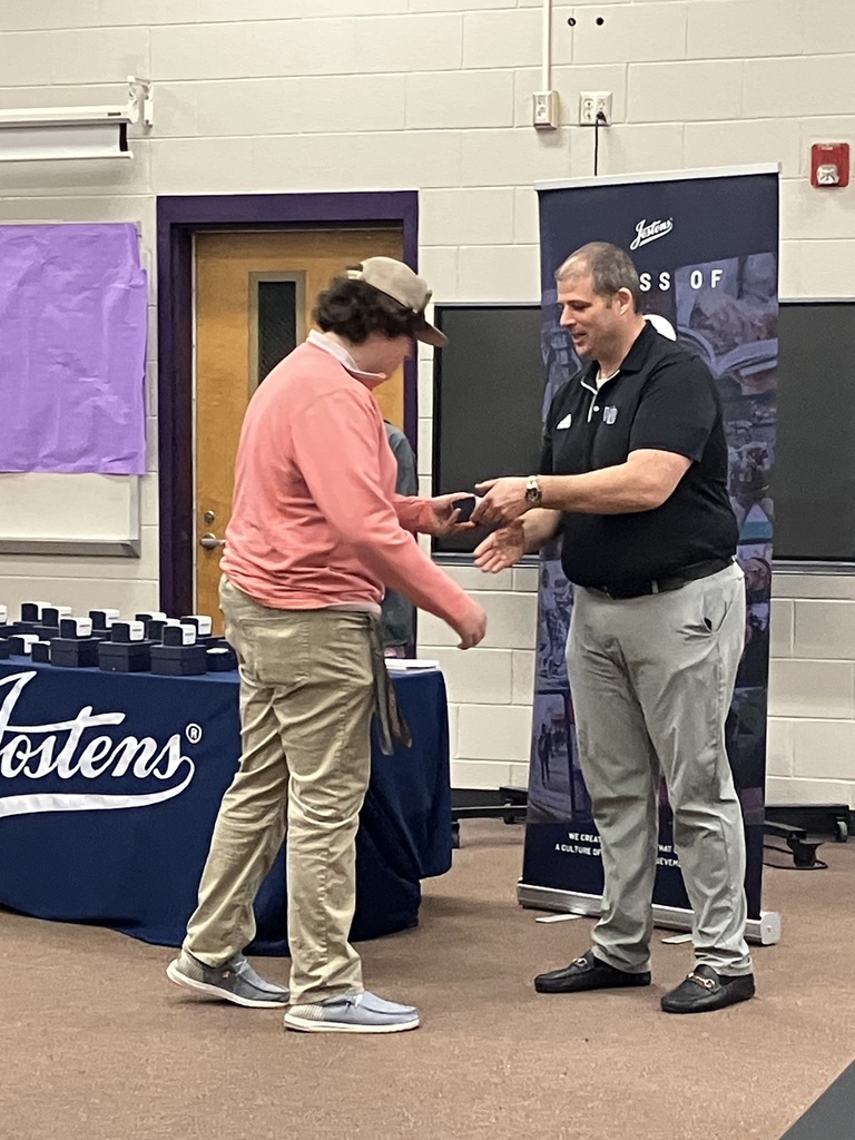 Principal hands a ring to a student and shakes his hand