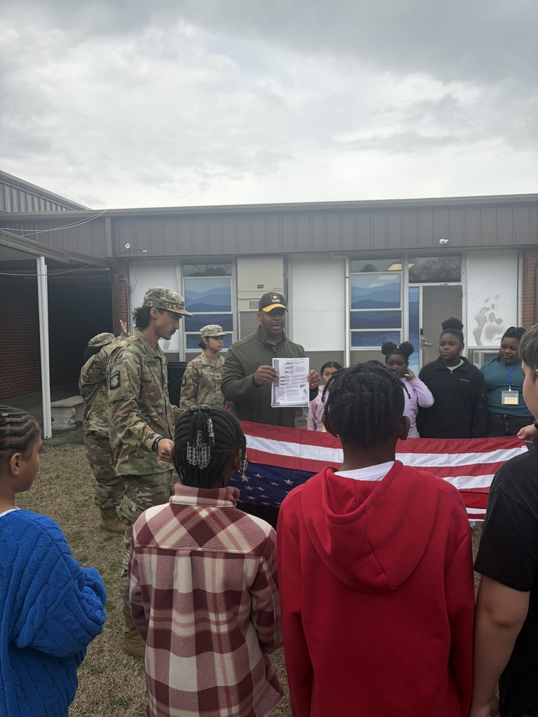 Students and JROTC members stand together in a circle outside as the flag is being folded.