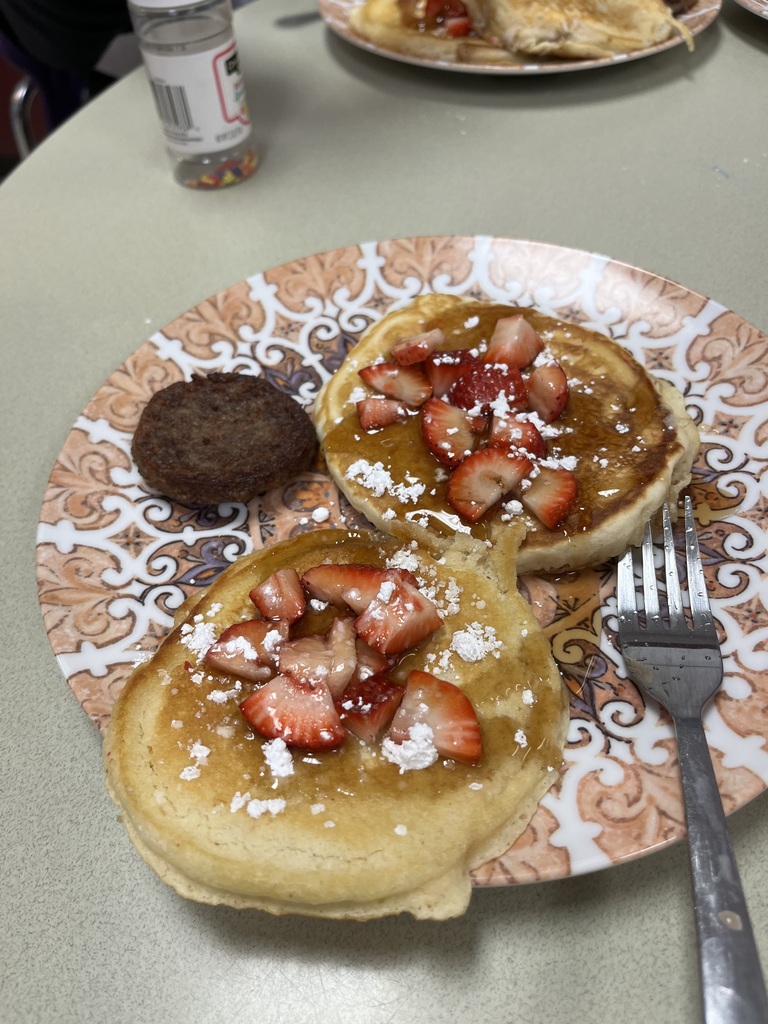 pancakes with strawberries, maple syrup,  and powdered sugar. 