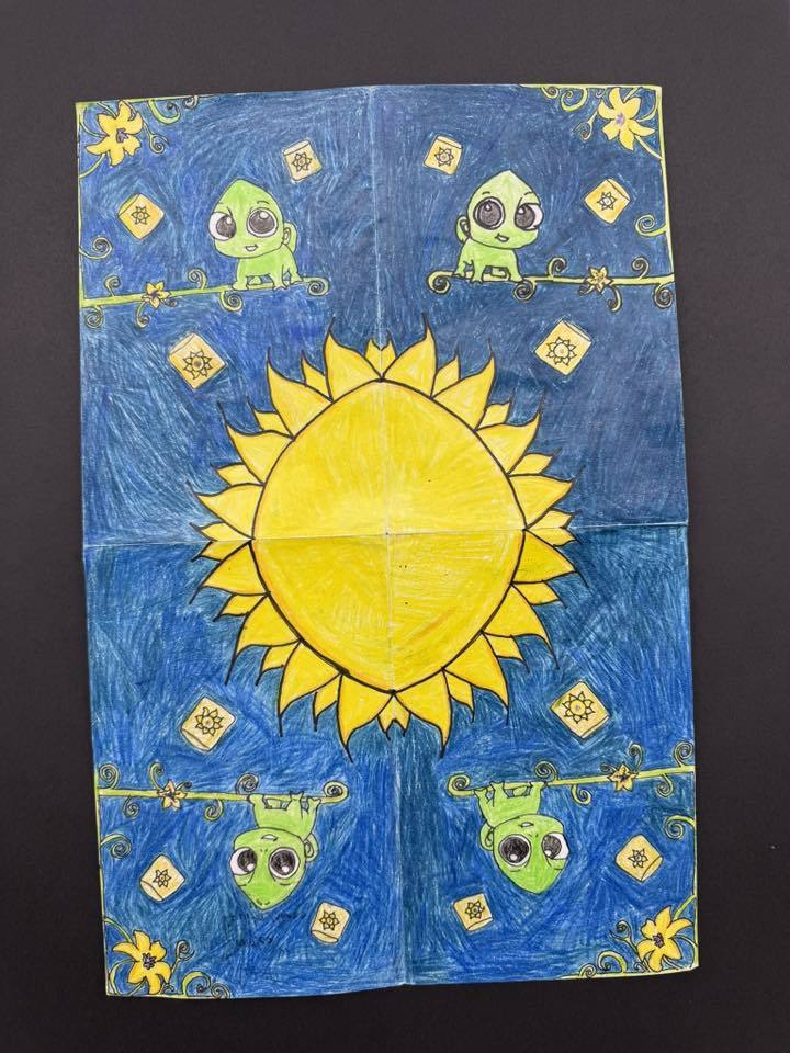 Colorful drawing featuring a large yellow sun centered on blue background with four cartoon-style green frogs and decorative floral accents.