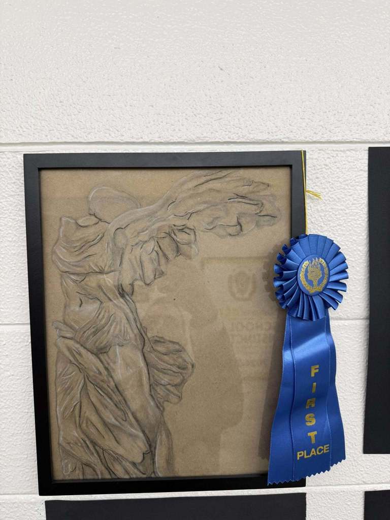 Charcoal-style drawing of a classical draped statue in profile, displayed with a blue “First Place” ribbon.