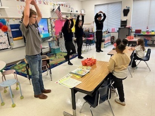 FFA students showing 2 elementary students how to do tree pose