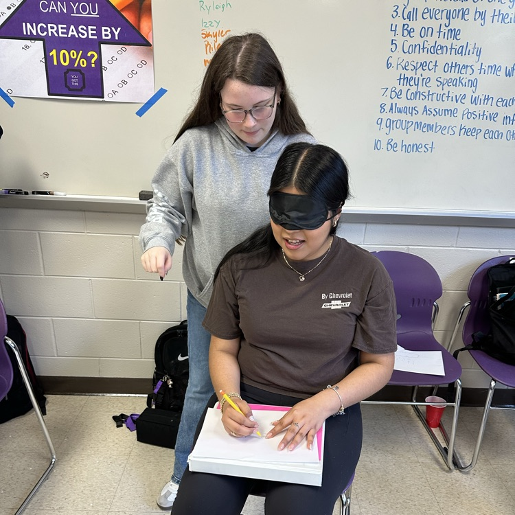 one student is drawing while another coaches